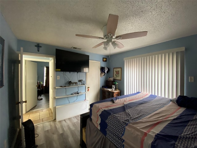 bedroom featuring ceiling fan, a textured ceiling, and light wood-type flooring