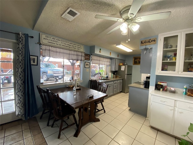 kitchen with sink, white cabinets, stainless steel fridge, ceiling fan, and a textured ceiling