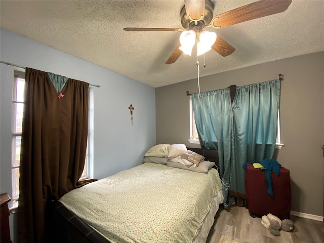 bedroom featuring ceiling fan, hardwood / wood-style floors, and a textured ceiling