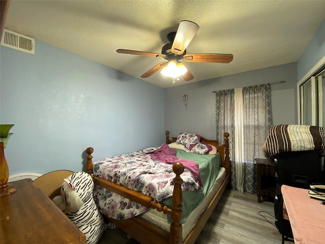 bedroom featuring a textured ceiling, ceiling fan, and light wood-type flooring