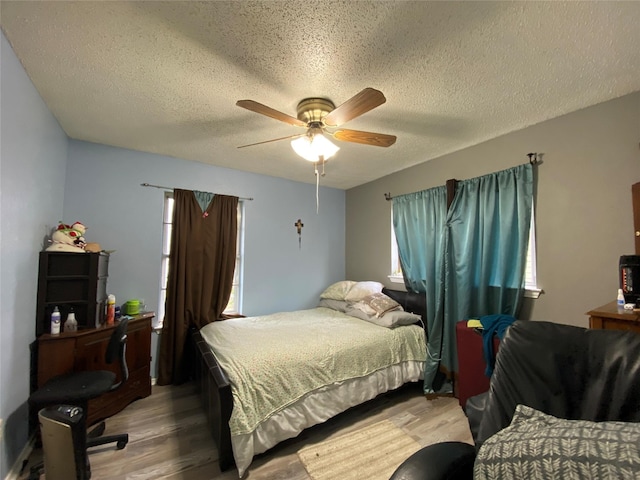 bedroom featuring ceiling fan, light hardwood / wood-style floors, and a textured ceiling