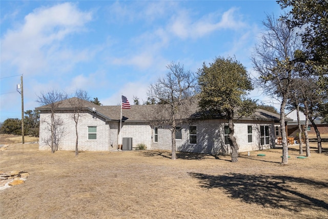 back of property featuring central AC unit and a yard