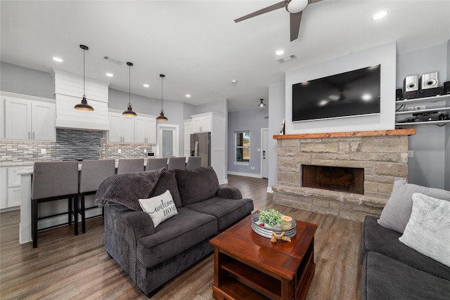 living room with ceiling fan, a fireplace, and dark hardwood / wood-style flooring