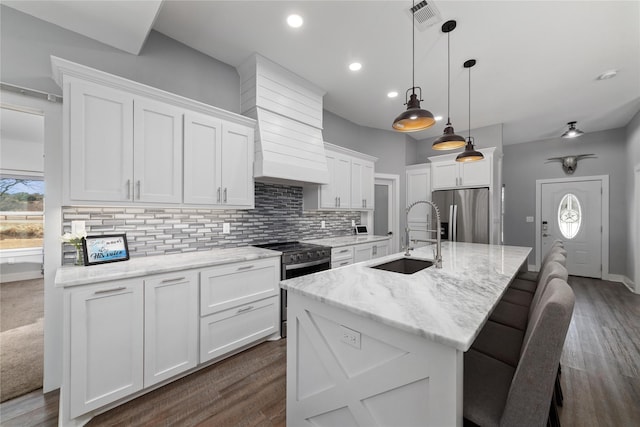 kitchen with white cabinetry, sink, stainless steel appliances, and a center island with sink