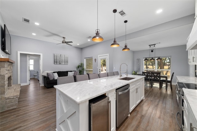 kitchen featuring appliances with stainless steel finishes, decorative light fixtures, white cabinetry, sink, and a kitchen island with sink