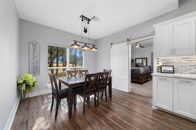 dining room featuring a barn door and dark hardwood / wood-style floors