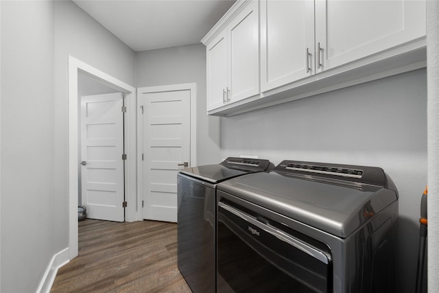 clothes washing area featuring cabinets, washer and dryer, and dark hardwood / wood-style flooring