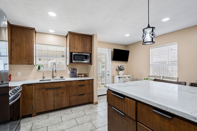 kitchen featuring sink, hanging light fixtures, light tile patterned floors, light stone counters, and stainless steel appliances