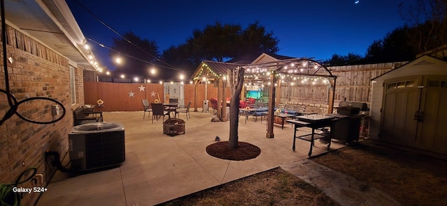 patio at twilight featuring a storage unit, cooling unit, and an outdoor fire pit