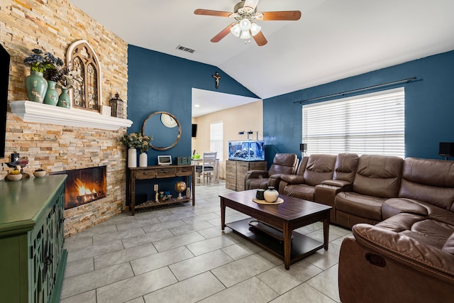 tiled living room with lofted ceiling, a stone fireplace, and ceiling fan