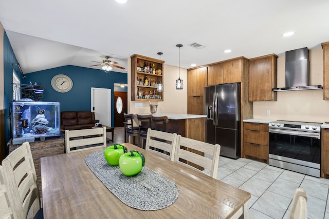 kitchen with pendant lighting, lofted ceiling, ceiling fan, stainless steel appliances, and wall chimney exhaust hood