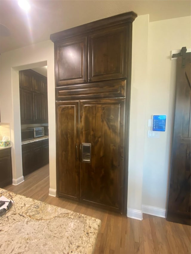 interior space with light stone counters, light hardwood / wood-style floors, and dark brown cabinets