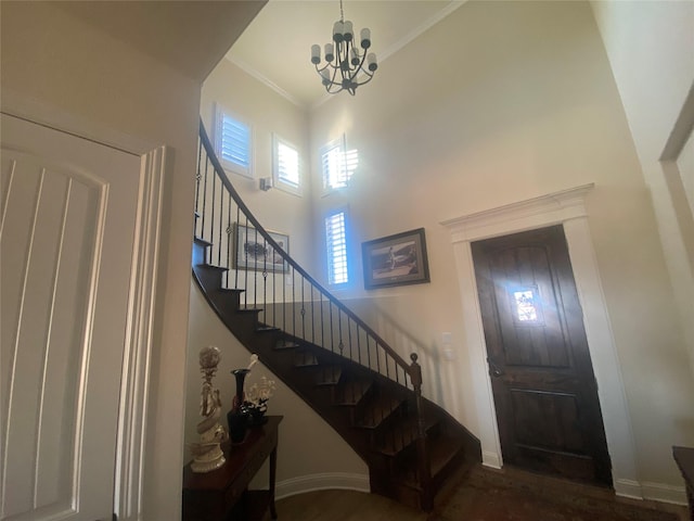 entryway featuring crown molding, a chandelier, and a towering ceiling