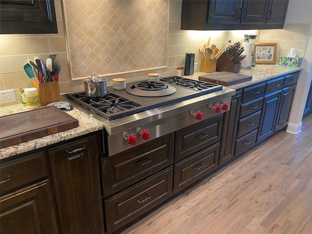 kitchen with stainless steel gas stovetop, backsplash, and light hardwood / wood-style floors