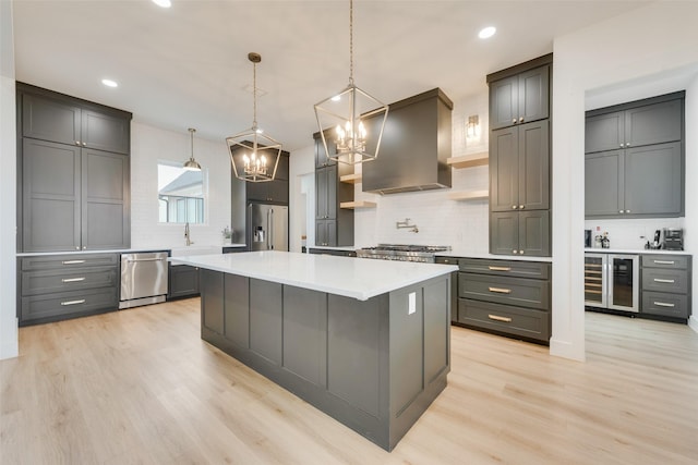 kitchen featuring stainless steel appliances, a large island, gray cabinets, and wall chimney range hood