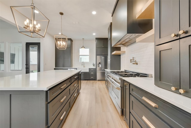 kitchen featuring pendant lighting, gray cabinets, premium appliances, a kitchen island, and exhaust hood