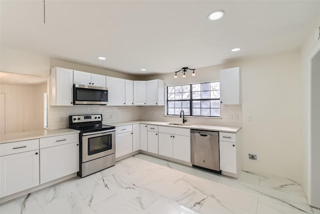 kitchen with stainless steel appliances, sink, decorative backsplash, and white cabinets