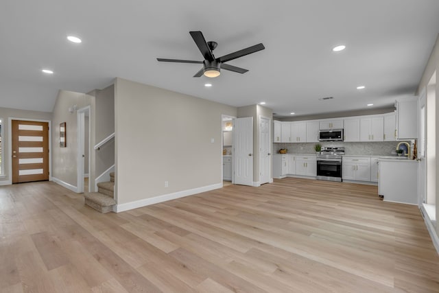 kitchen featuring sink, light hardwood / wood-style flooring, white cabinetry, backsplash, and stainless steel appliances