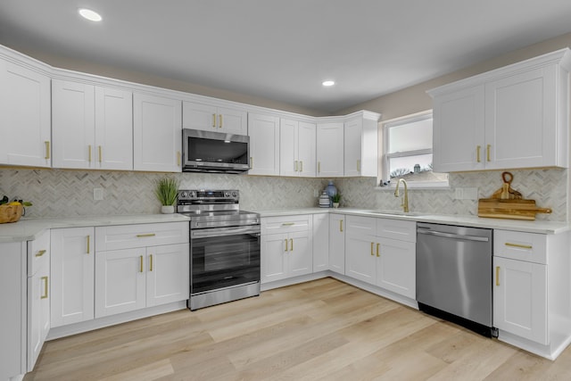 kitchen featuring sink, white cabinets, decorative backsplash, light hardwood / wood-style floors, and stainless steel appliances