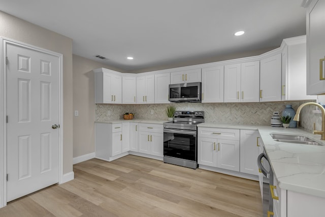 kitchen featuring sink, light hardwood / wood-style flooring, stainless steel appliances, white cabinets, and decorative backsplash