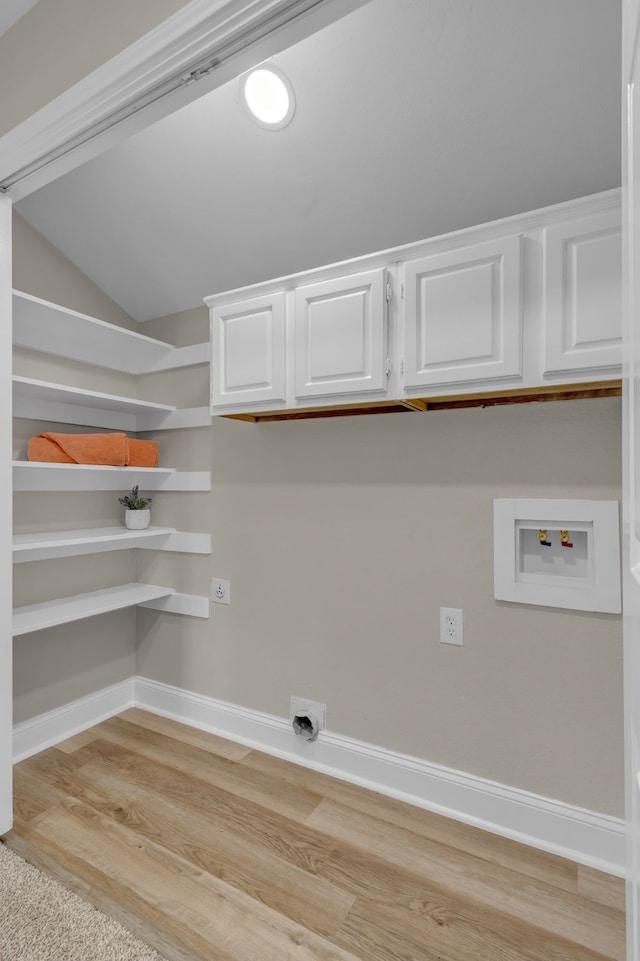 laundry room with electric dryer hookup, hookup for a washing machine, cabinets, and light wood-type flooring