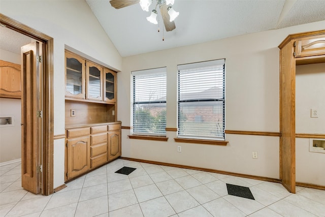 kitchen featuring light tile patterned flooring, ceiling fan, vaulted ceiling, and a textured ceiling