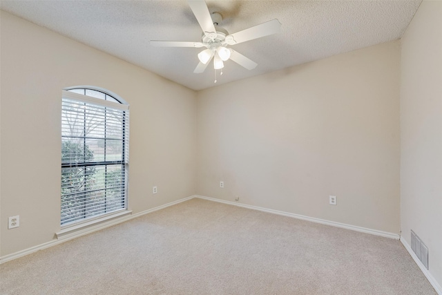 carpeted empty room featuring ceiling fan and a textured ceiling