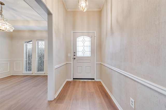 entryway featuring crown molding, wood-type flooring, and a chandelier