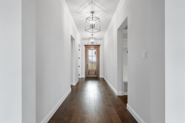 doorway with an inviting chandelier, ornamental molding, and dark hardwood / wood-style flooring