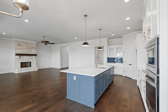 kitchen featuring appliances with stainless steel finishes, blue cabinets, sink, white cabinets, and a kitchen island with sink