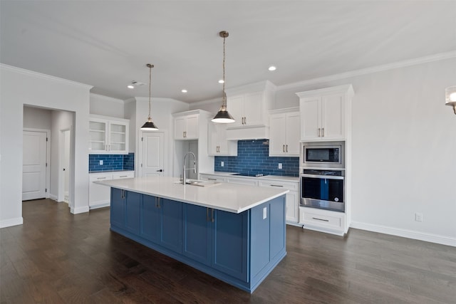 kitchen with appliances with stainless steel finishes, sink, white cabinets, hanging light fixtures, and a center island with sink