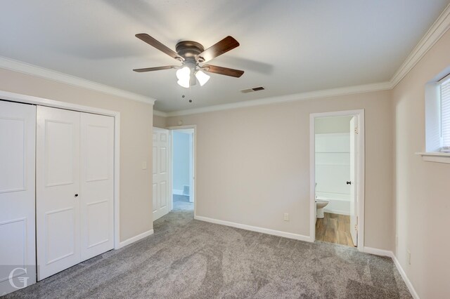 unfurnished bedroom featuring baseboards, visible vents, light colored carpet, crown molding, and a closet