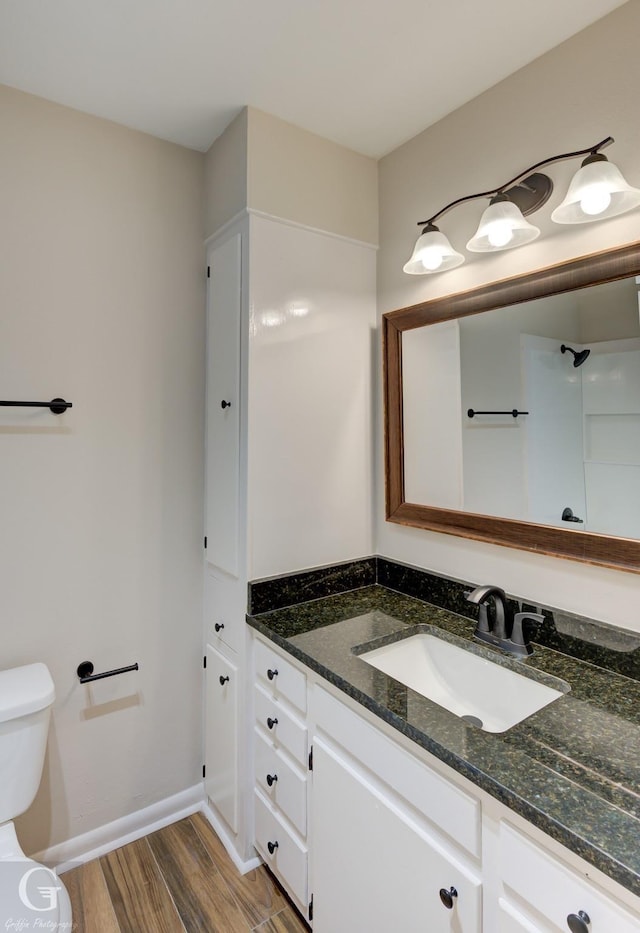 full bath with toilet, baseboards, wood finished floors, and vanity