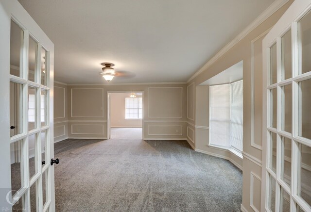 unfurnished living room with ceiling fan, carpet floors, ornamental molding, a brick fireplace, and french doors