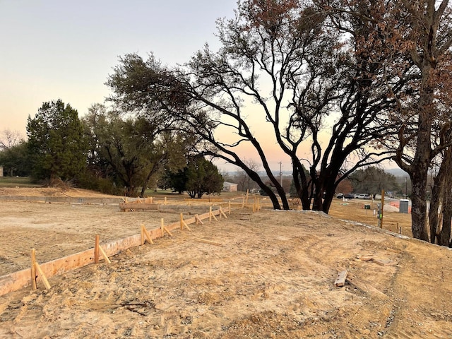 yard at dusk featuring a rural view