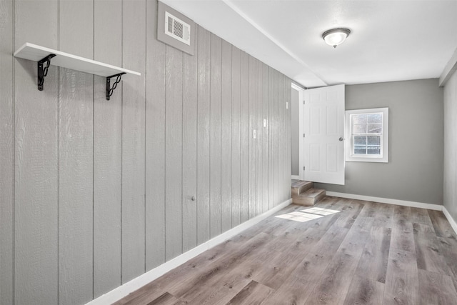 interior space with light hardwood / wood-style flooring and wood walls