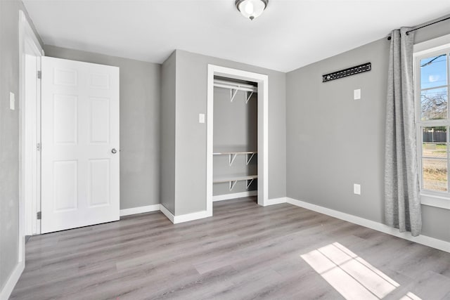 unfurnished bedroom with a closet, multiple windows, and light wood-type flooring