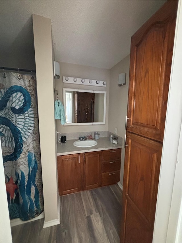 bathroom with wood-type flooring, vanity, and a textured ceiling