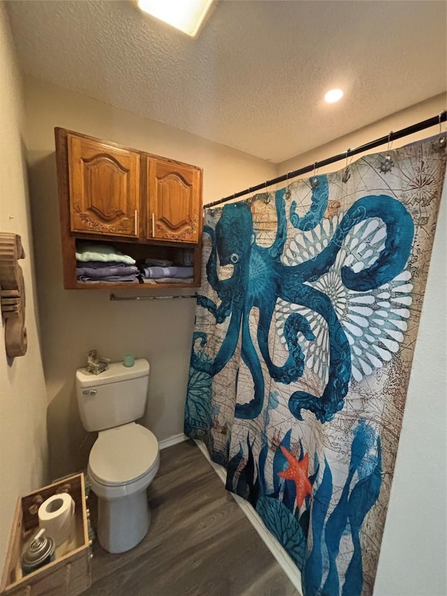 bathroom with wood-type flooring, toilet, curtained shower, and a textured ceiling