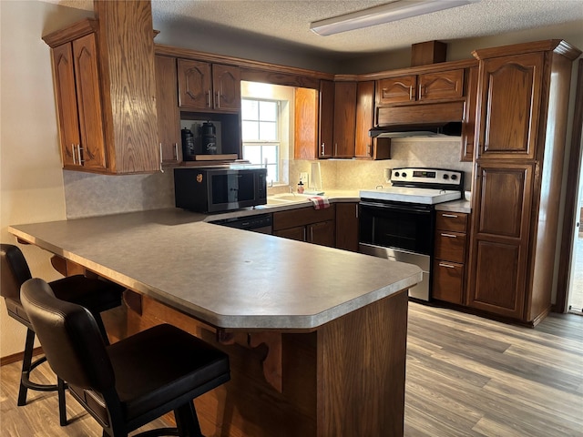 kitchen with appliances with stainless steel finishes, kitchen peninsula, and light wood-type flooring