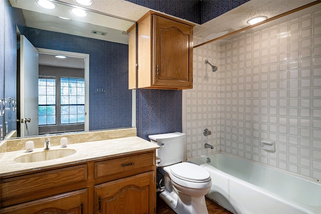 full bathroom featuring tiled shower / bath, vanity, and toilet