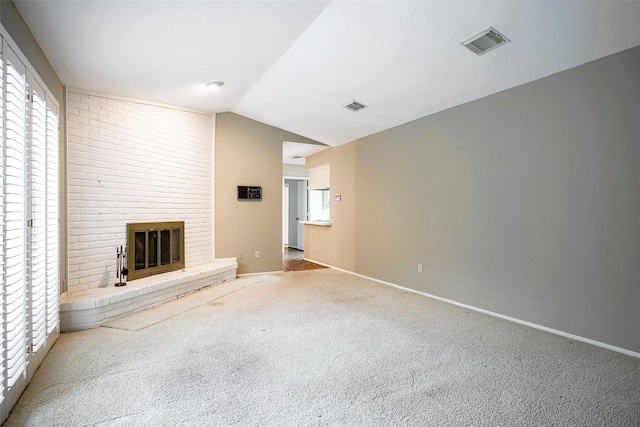 unfurnished living room with lofted ceiling, a brick fireplace, and carpet floors