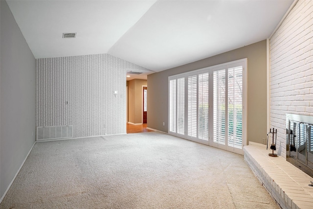 unfurnished living room with light colored carpet, lofted ceiling, and a brick fireplace