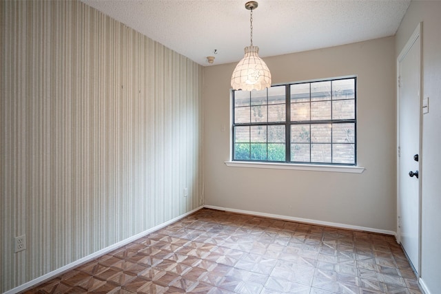 unfurnished dining area with parquet flooring and a textured ceiling