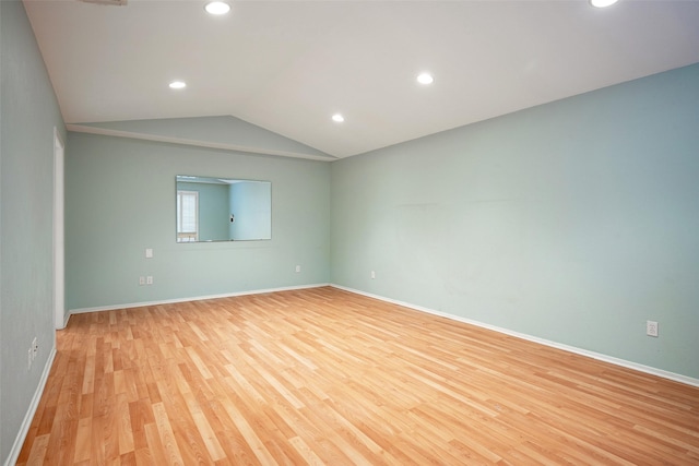 spare room featuring lofted ceiling and light hardwood / wood-style flooring