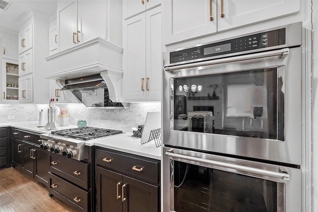 kitchen featuring tasteful backsplash, stainless steel appliances, light wood-type flooring, and white cabinets