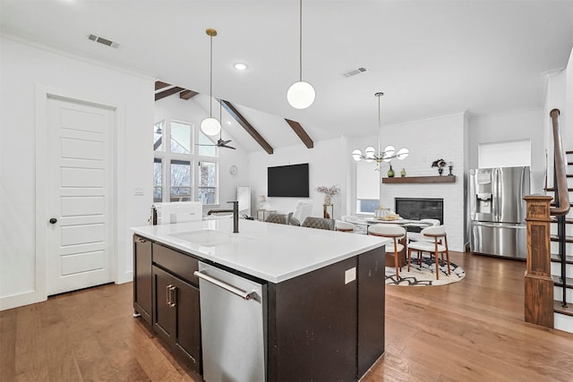 kitchen with pendant lighting, a center island with sink, light hardwood / wood-style flooring, and appliances with stainless steel finishes