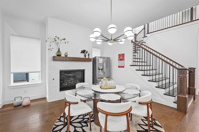 dining area featuring a fireplace, ornamental molding, dark hardwood / wood-style floors, and a chandelier