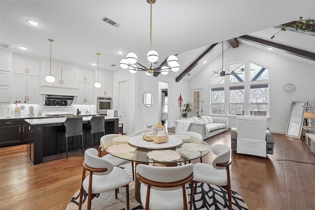 dining space featuring beamed ceiling, ceiling fan with notable chandelier, hardwood / wood-style floors, and high vaulted ceiling