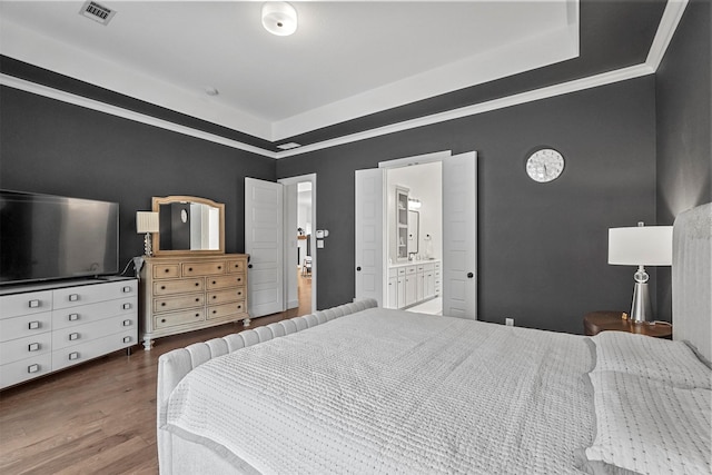 bedroom with crown molding, dark wood-type flooring, and ensuite bathroom